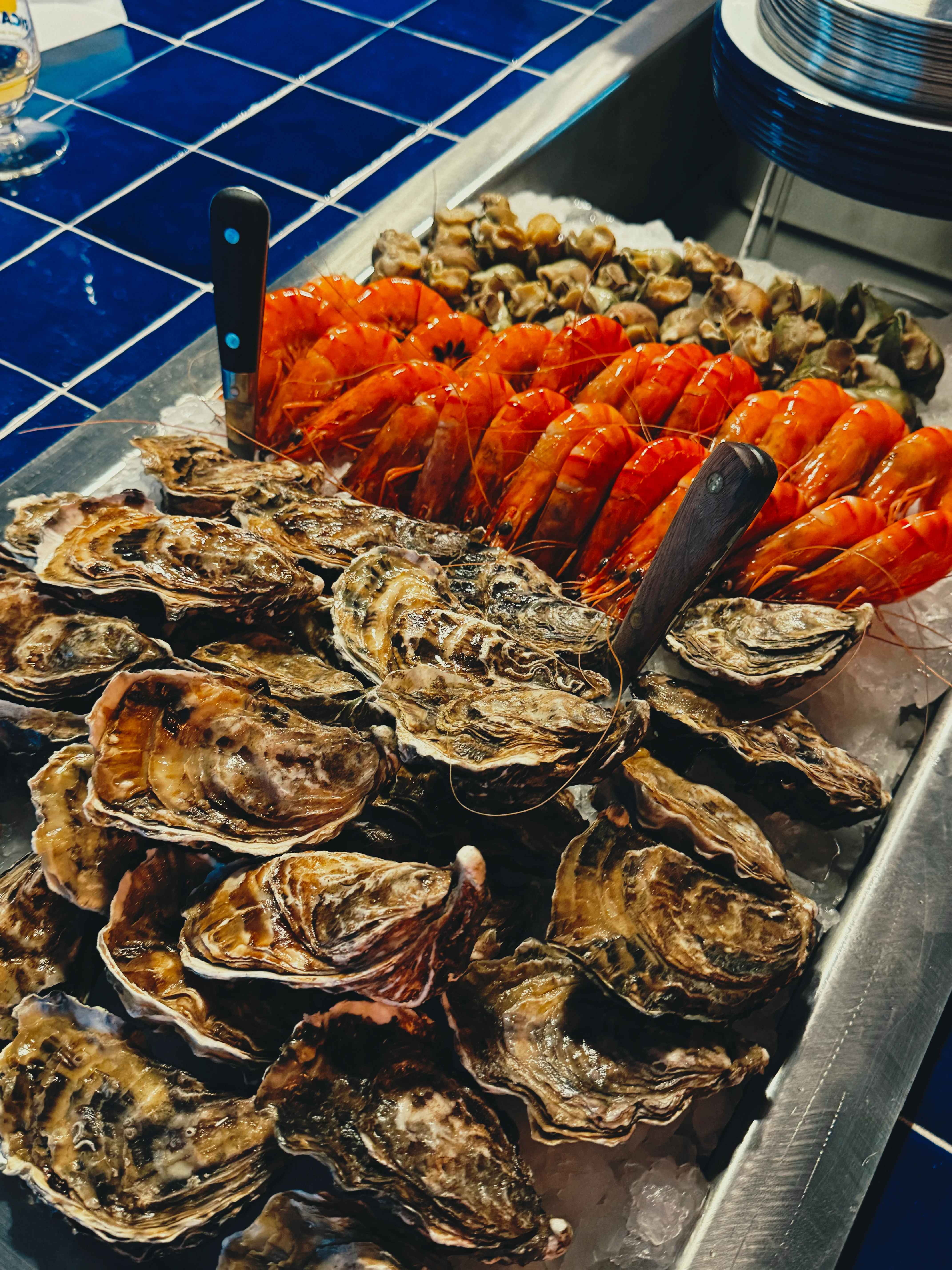 Comptoir garni d'huîtres et crevettes sur fond de carrelage bleu